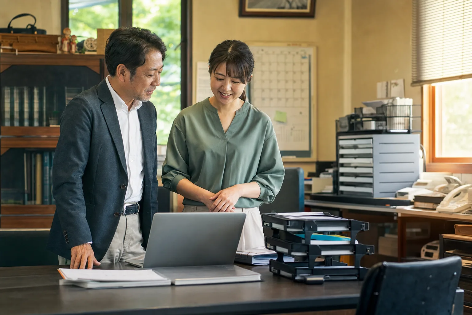 日本の中小企業の経営者と社員が、改善した業務をノートパソコンで確認している様子